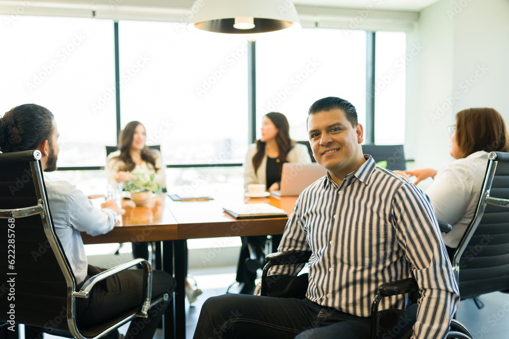 Mid adult disabled businessman sitting in office meeting with colleagues