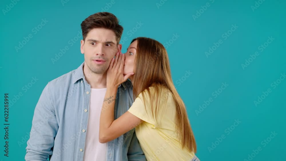 Woman tells man secret into ear covering mouth with palm Woman tells man secret into ear covering mouth with palm