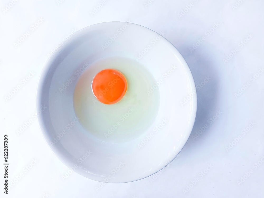 Raw chicken eggs in a bowl over white background. Perfectly round raw egg yolk. egg on white plate Raw chicken eggs in a bowl over white background. Perfectly round raw egg yolk. egg on white plate