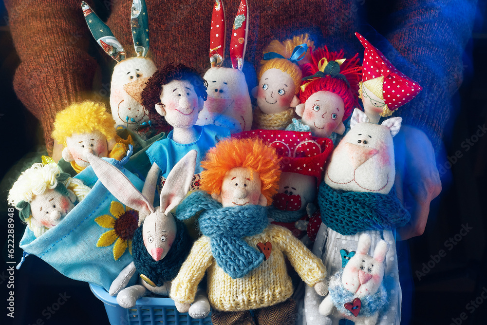 Many fabric dolls and toys in colorful knitted scarves in the basket