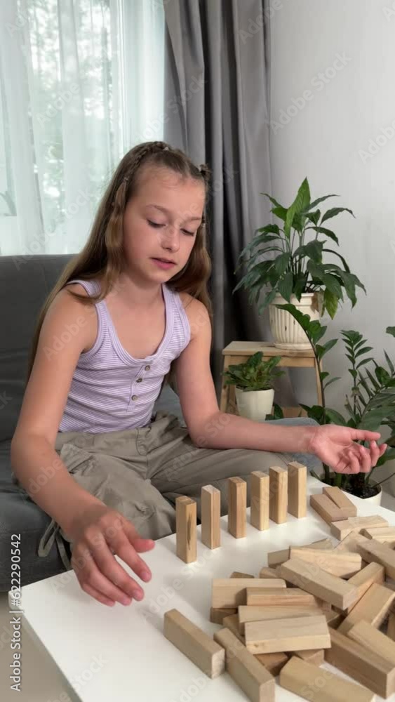 a child plays at home with wooden blocks, a girl plays educational games, builds with the help of a wooden constructor, entertainment at home a child plays at home with wooden blocks, a girl plays educational games, builds with the help of a wooden constructor, entertainment at home