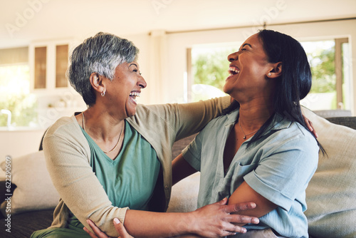 Funny, senior mother and hug daughter in home, bonding and laughing together. Happy, elderly mom and embrace woman, relax and smile with care, love and enjoying time on living room sofa with family.