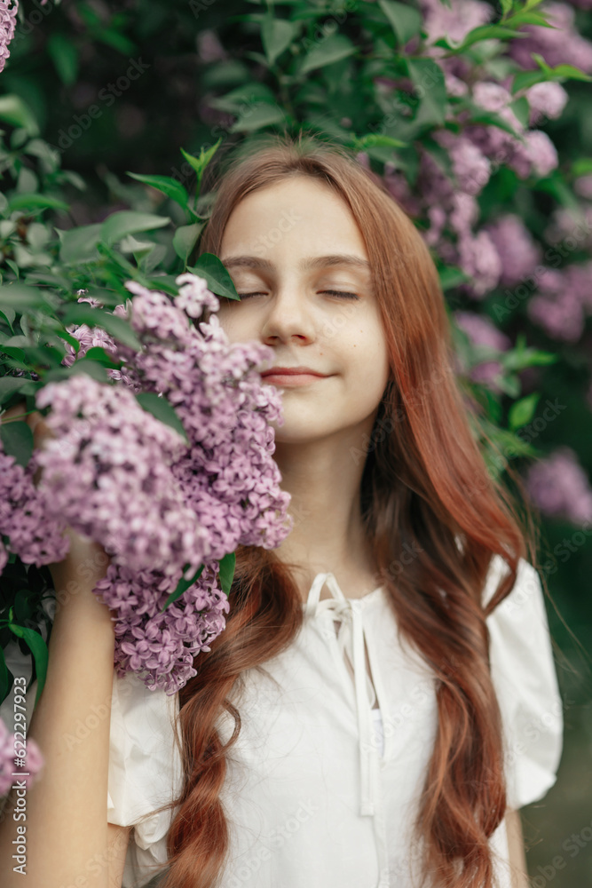 Young pretty happy smiling girl in white dress standing with closed eyes with blooming branches of lilac in spring garden or park, vertical outdoor lifestyle portrait, idea of beauty, freshness, relax Young pretty happy smiling girl in white dress standing with closed eyes with blooming branches of lilac in spring garden or park, vertical outdoor lifestyle portrait, idea of beauty, freshness, relax