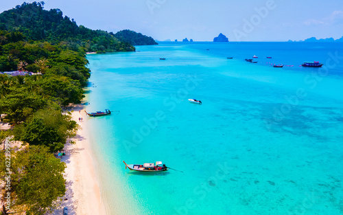drone view at the beach of Koh Kradan island in Thailand, aerial view over Koh Kradan Island Trang with longtail boats in the ocean on a sunny day