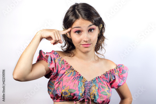 Adult girl points her finger at her head on a white background