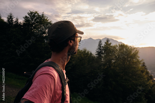 Back view of hiker admiring sunset.Nature view of mountains and hills with woods at sunset.Mountain sunset watcher.