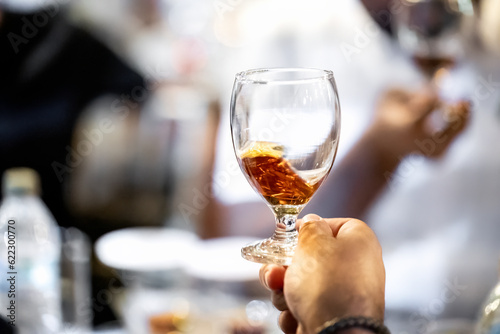 Close up of copa glass with splashing rum in a male hand. Best room tasting liquors events © Bankerok