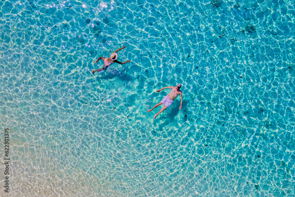 drone view of a men and woman swimming in the blue turqouse colored ocean of Koh Kradan island in Thailand