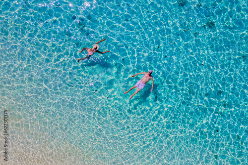 drone view of a men and woman swimming in the blue turqouse colored ocean of Koh Kradan island in Thailand