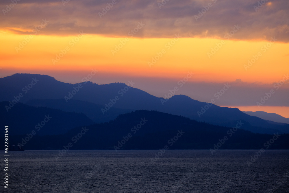 Sunset with pink, orange and purple sky above Inside Passage in British Columbia, Canada seen from cruiseship cruise ship liner returning from Alaska with mountains, shore and coast line