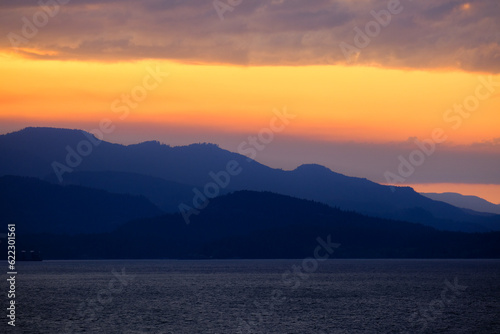 Sunset with pink, orange and purple sky above Inside Passage in British Columbia, Canada seen from cruiseship cruise ship liner returning from Alaska with mountains, shore and coast line