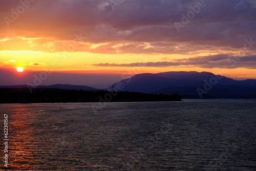 Sunset with pink  orange and purple sky above Inside Passage in British Columbia  Canada seen from cruiseship cruise ship liner returning from Alaska with mountains  shore and coast line
