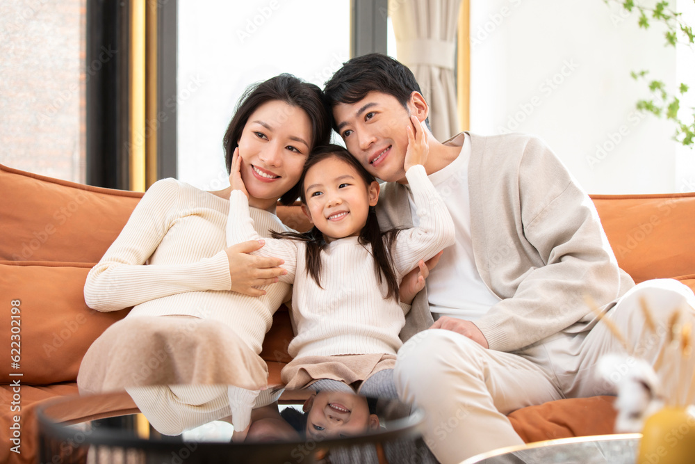 Happy young Chinese family sitting on sofa Happy young Chinese family sitting on sofa