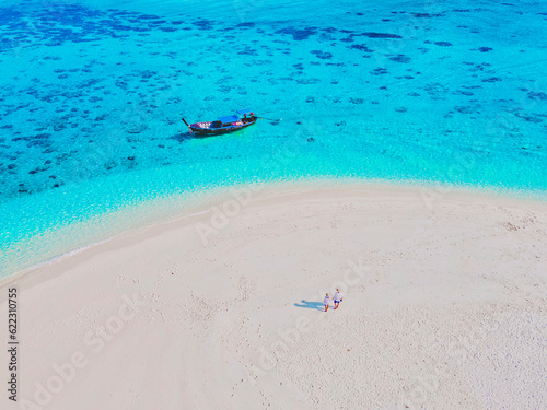 a couple of men and women at a white sandbank in the ocean of Koh Lipe Island Southern Thailand, with turqouse colored ocean and white sandy beach sandbar at Ko Lipe on a sunny day