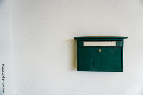 Vintage green mailbox displayed on a white wall with copyspace composition for text