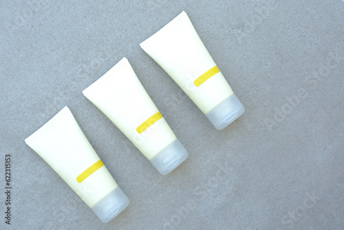 three tubes of cream on a gray background