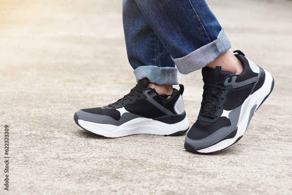 Close up male teenager wears sneakers shoes and blue jeans legs. Concept, fashion, lifestyle. Comfortable footwears and costumes for going out, journey or traveling. cool casual fashion for teens 