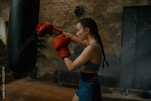 Healthy strong girl fighter boxing with punching bag having workout training