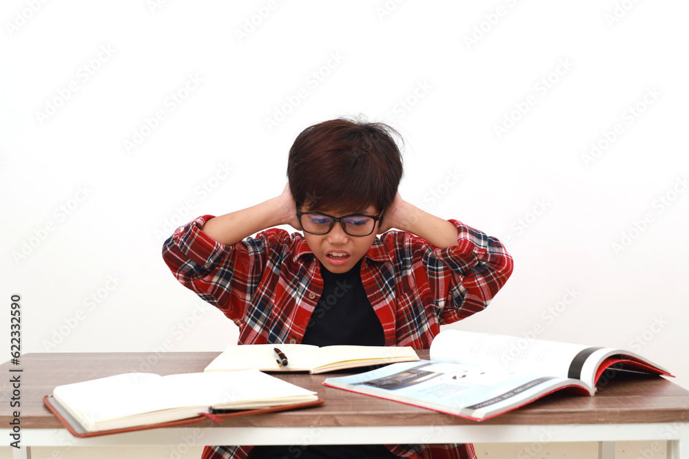 Depressed asian student holding his head while studying on the desk. Isolated on white Depressed asian student holding his head while studying on the desk. Isolated on white