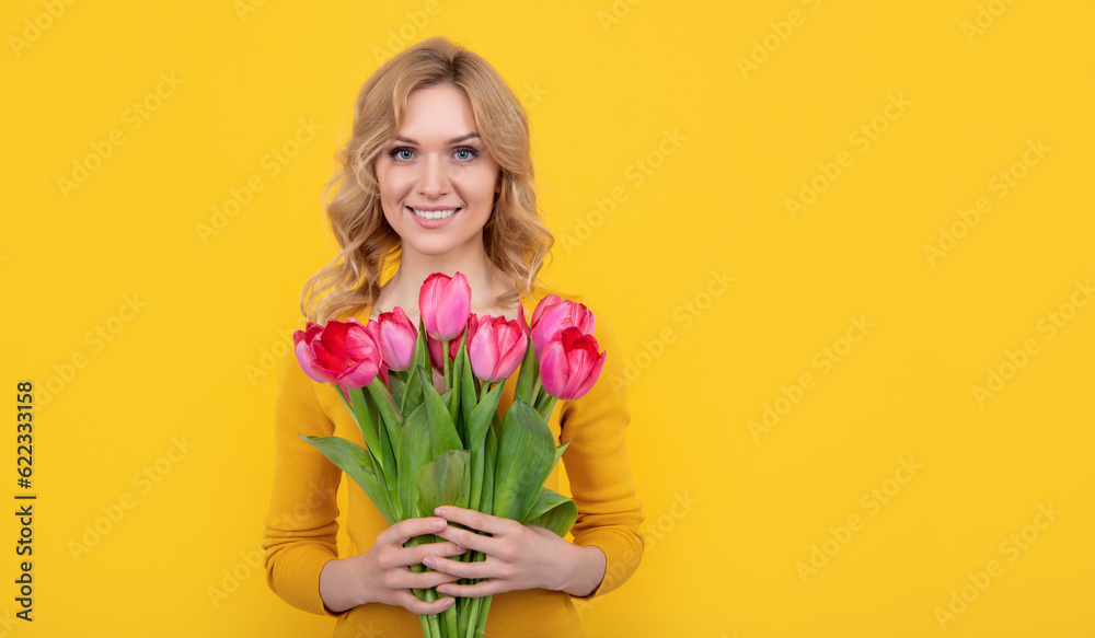 glad young girl with spring tulip flowers on yellow background glad young girl with spring tulip flowers on yellow background