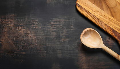 Abstract food background. Top view of dark rustic kitchen table with wooden cutting board and cooking spoon, frame. Banner or template with copy space for your design. Kitchen utensils objects