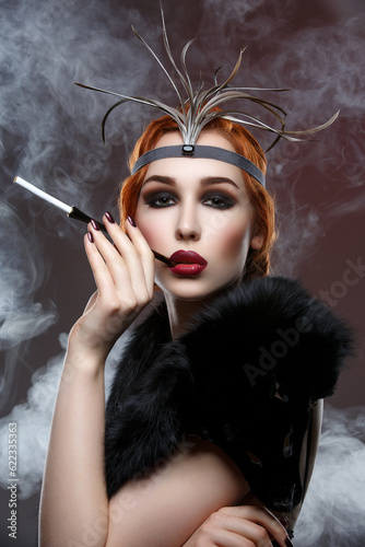 Beautiful young woman with smoky eyes and full red lips holding cigarette holder. Vintage head piece. Retro styling. Studio beauty shot over smoky background. Copy space.