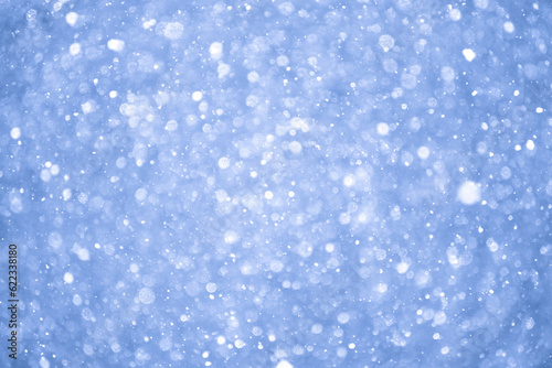 Abstract Blue Christmas Background with Real Snow. Blurred Snowflakes Photo.
