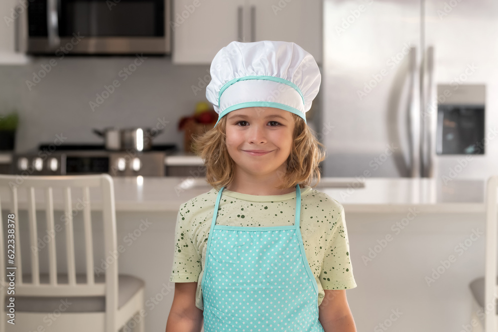 Portrait of funny child chef in kitchen. Child chef cook prepares food at kitchen. Kids cooking. Teen boy with apron and chef hat preparing a healthy meal. Portrait of funny child chef in kitchen. Child chef cook prepares food at kitchen. Kids cooking. Teen boy with apron and chef hat preparing a healthy meal.