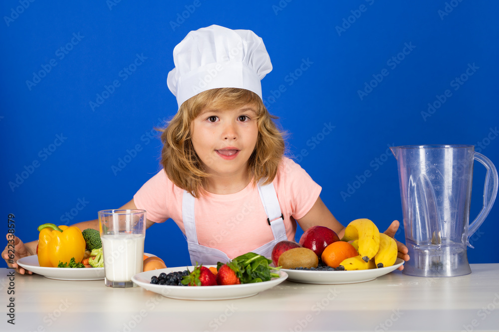 Fruits and vegetables for kids. Child chef isolated on blue. Funny little kid chef cook wearing uniform cook cap and apron cooked food in the kitchen. Fruits and vegetables for kids. Child chef isolated on blue. Funny little kid chef cook wearing uniform cook cap and apron cooked food in the kitchen.