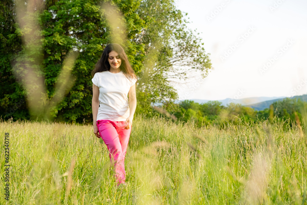 A young woman walks across a field. A walk in nature in the summer. A young woman walks across a field. A walk in nature in the summer.