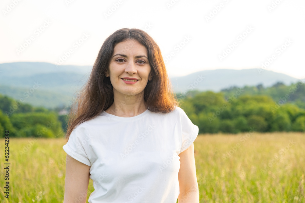 Portrait of a 35-year-old European woman smiling while looking at the camera while walking in nature in a field. Portrait of a 35-year-old European woman smiling while looking at the camera while walking in nature in a field.