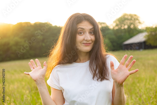 Brunette woman shows her palms, ten fingers, raising her hands up