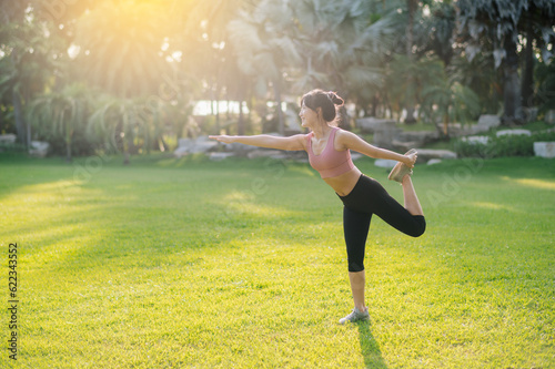 Embrace healthy outdoor lifestyle with image of fit Asian 30s woman wearing pink sportswear stretches muscles in public park before refreshing run, embodying the wellness concept and joy of fitness.