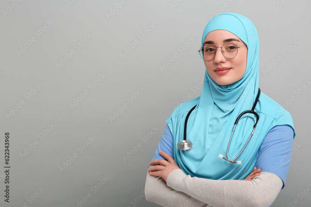 Muslim woman wearing hijab and medical uniform with stethoscope on light gray background, space for text Muslim woman wearing hijab and medical uniform with stethoscope on light gray background, space for text