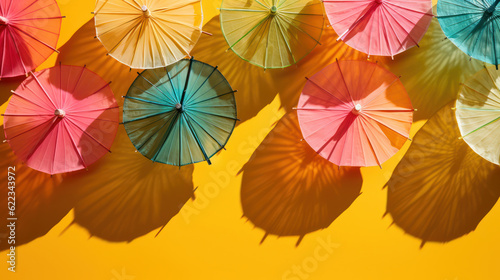 Colorful cocktail umbrellas and shadows with yellow background