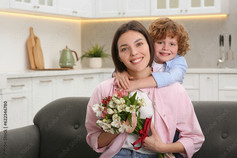 Little son congratulating his mom with Mother`s day at home, space for text. Woman holding bouquet of beautiful flowers Little son congratulating his mom with Mother`s day at home, space for text. Woman holding bouquet of beautiful flowers