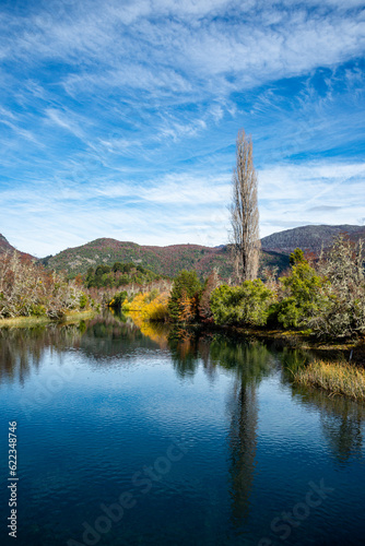 View of the banks of the Manso River and their reflections, from a bridge on an autumn afternoon. Bariloche, Rio Negro, Argentina.