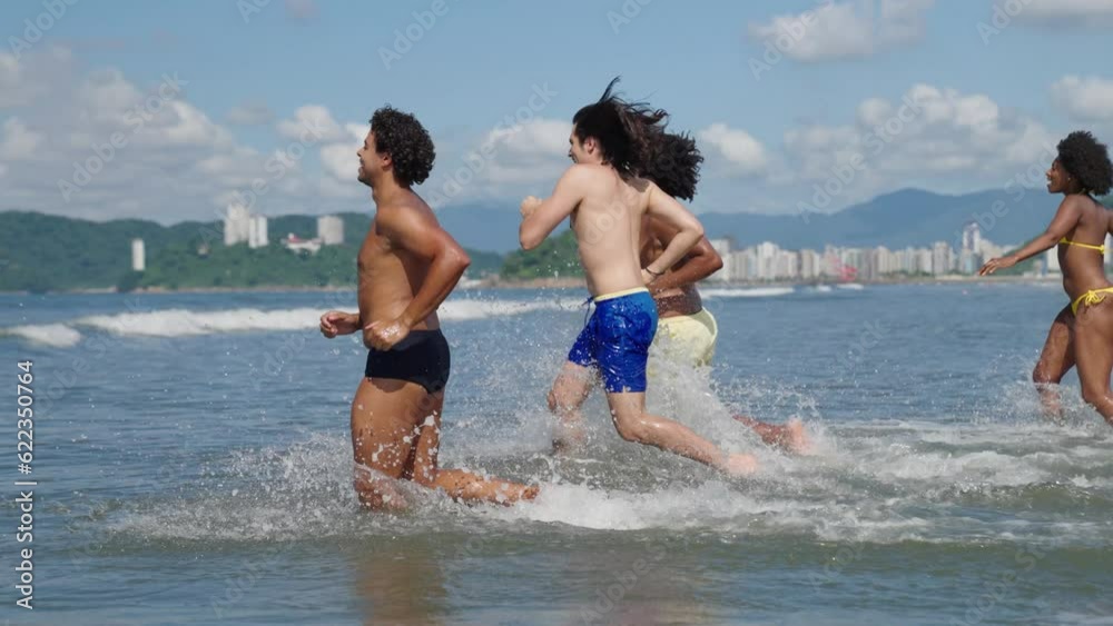 group of friends having fun running into the ocean at the beach in slow motion
group of friends having fun running into the ocean at the beach in slow motion