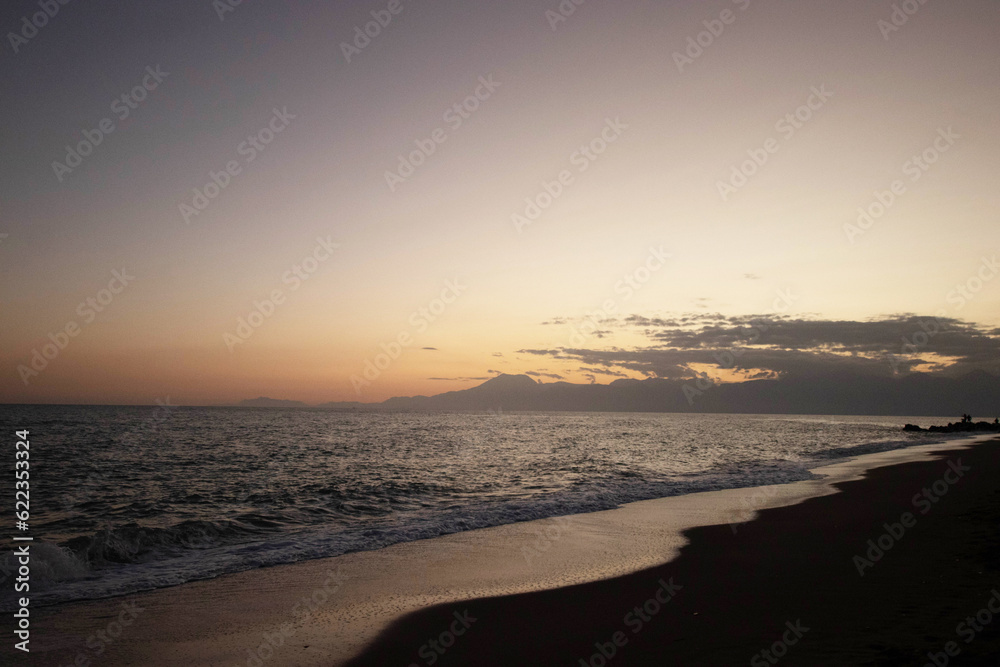 Beautiful view of the sea, waves and mountains at sunset. The horizon above the water.