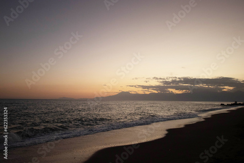Beautiful view of the sea  waves and mountains at sunset. The horizon above the water.