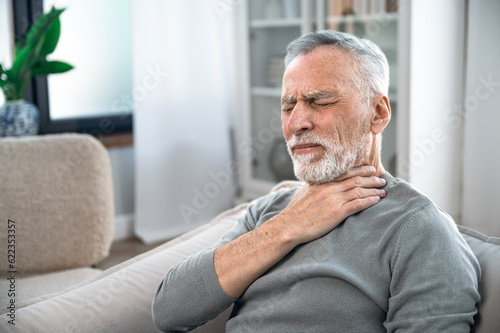 Mature man suffering from strong throat sore photo