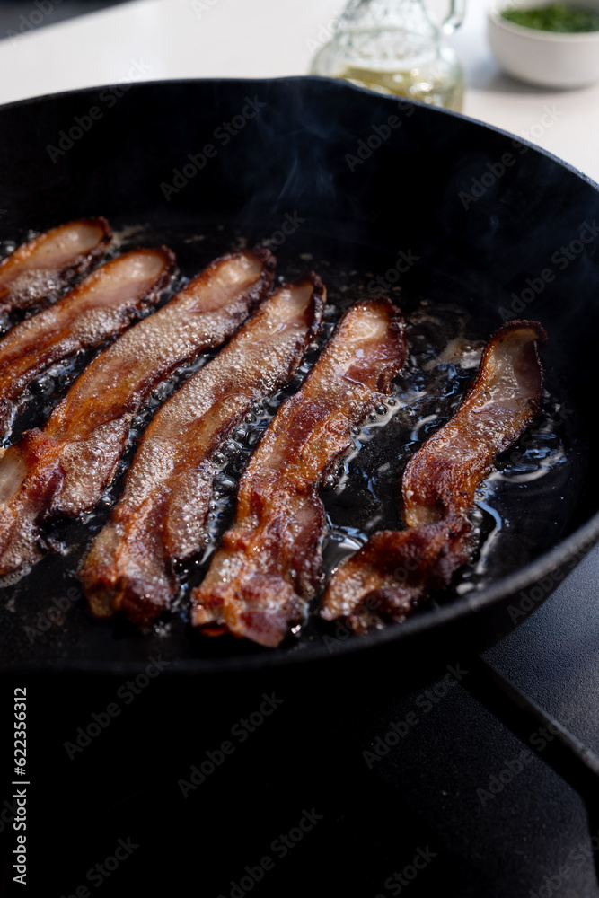 Bacon frying is a cast iron black skillet Bacon frying is a cast iron black skillet