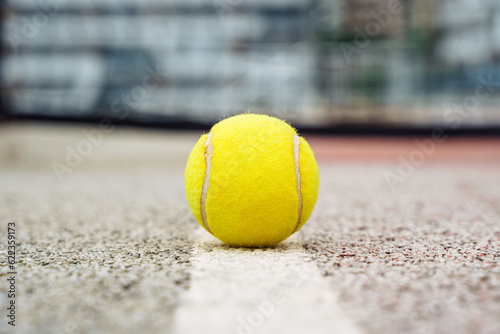 Closeup view of yellow tennis ball lying on acrylic tennis hard court surface with empty blank copy space.