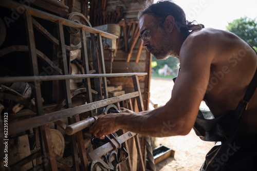 Close up of a blacksmith checking the measurements of a grating in his workshop.