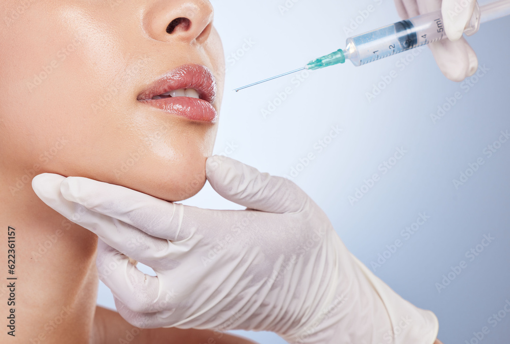Mouth, botox and plastic surgery with hands on the face of a woman for cosmetic surgery in studio on a blue background. Lips, filler or beauty and a female patient with her doctor for an injection Mouth, botox and plastic surgery with hands on the face of a woman for cosmetic surgery in studio on a blue background. Lips, filler or beauty and a female patient with her doctor for an injection