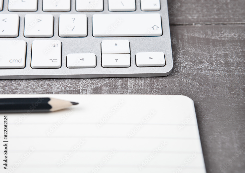 Keyboard with pencil on open notebook sheet on office desk Keyboard with pencil on open notebook sheet on office desk