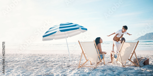 Beach, travel and family relaxing while on a vacation, adventure or weekend trip for summer. Freedom, bonding and father flying his boy child sitting by the ocean with his wife on a tropical holiday.