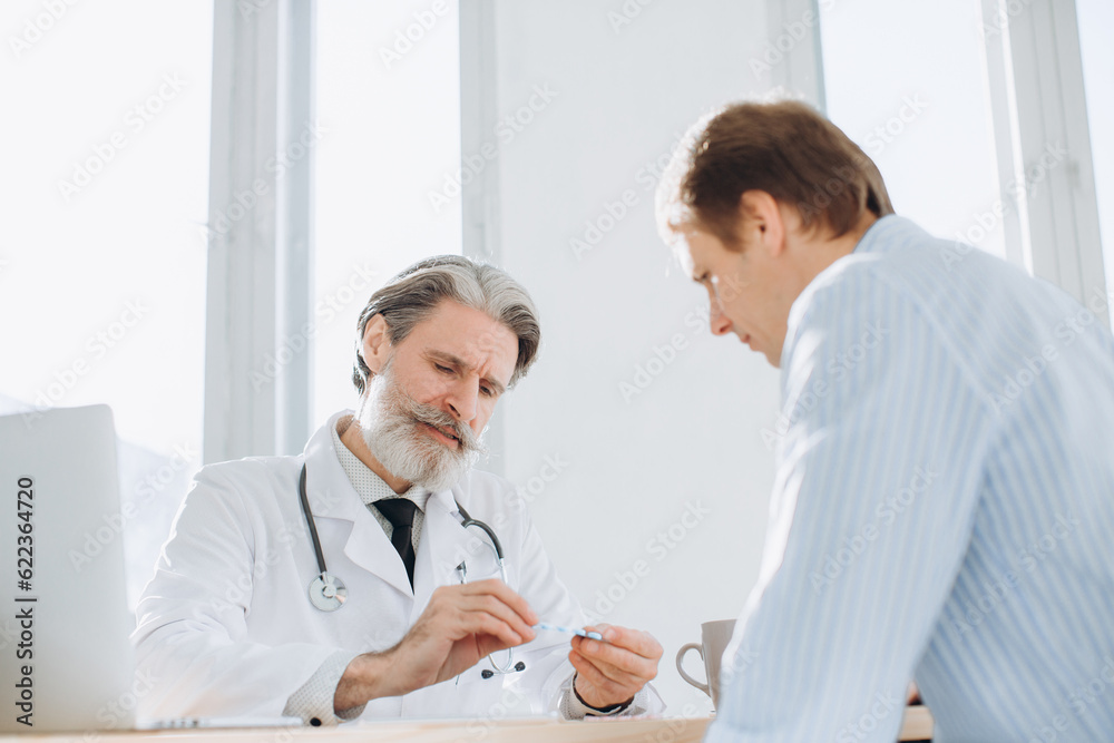 Mature doctor prescribing pills to his patient Mature doctor prescribing pills to his patient