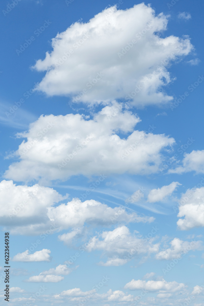 Blue cloudy sky with many beautiful white fluffy cumulus clouds in sunlight background texture Blue cloudy sky with many beautiful white fluffy cumulus clouds in sunlight background texture