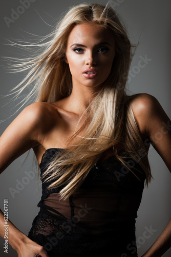 hairstyle, haircare and fashion concept - natural beautiful blond woman portrait with flying hair on grey background